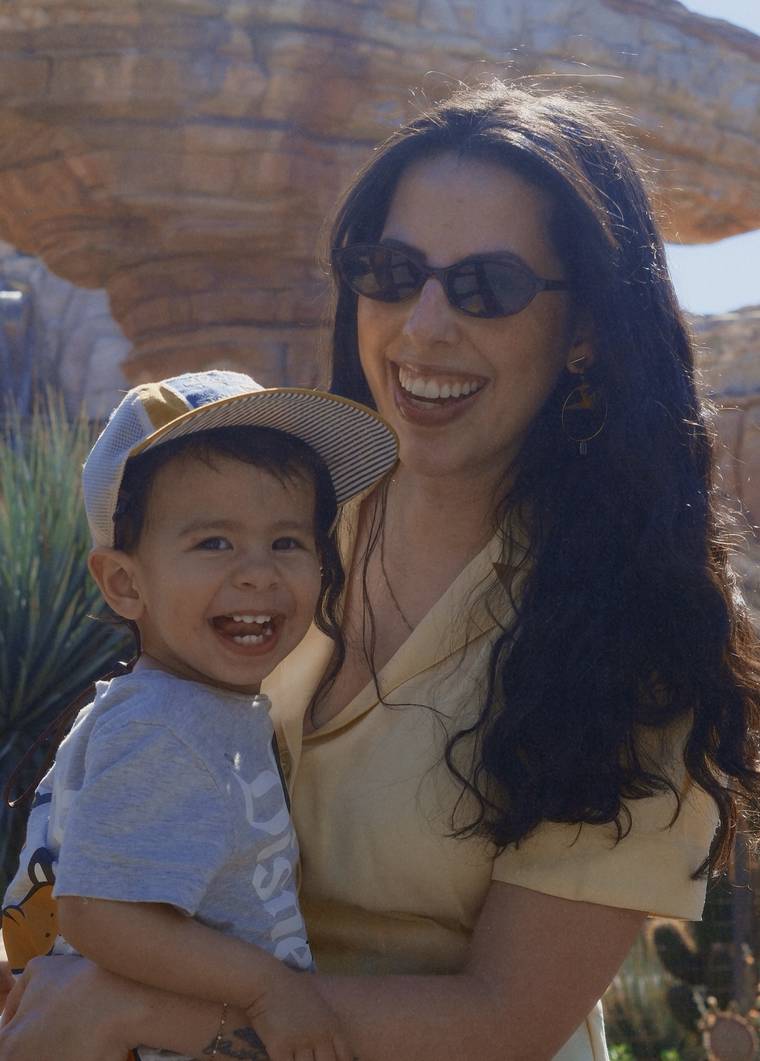 Mari smiling and holding her young son outdoors