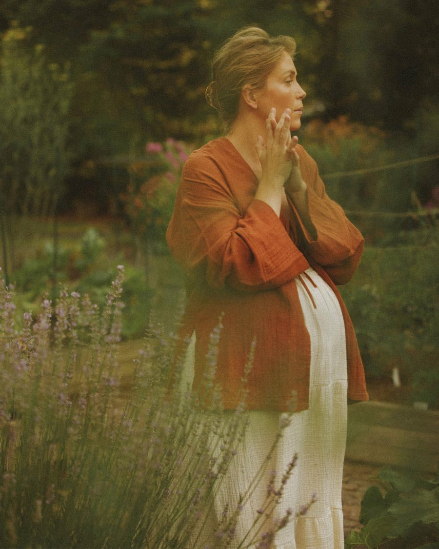 An expecting mother standing peacefully in a garden of lavender