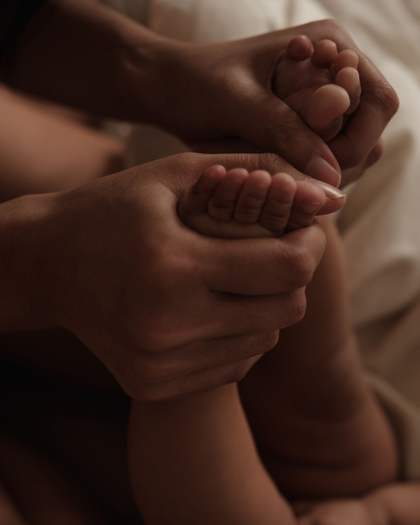 A parent's hands gently holding a newborn's feet