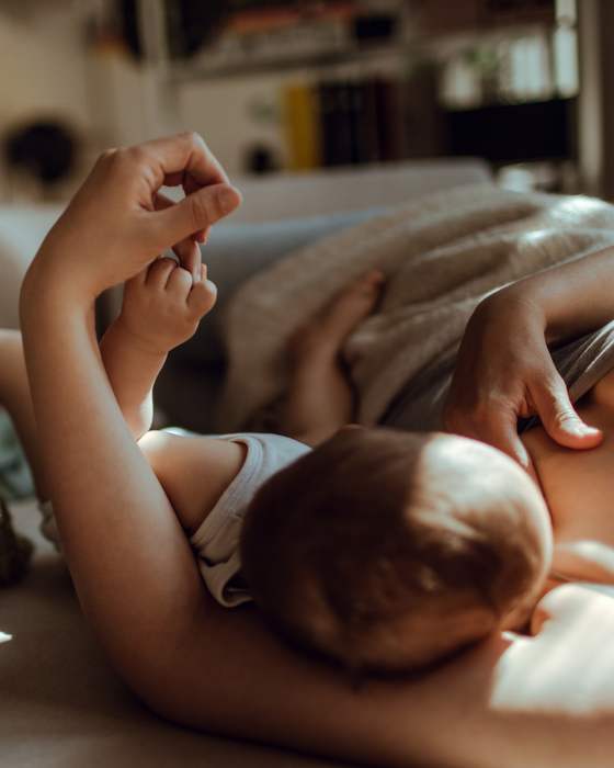 A mother nursing her baby in soft light at home
